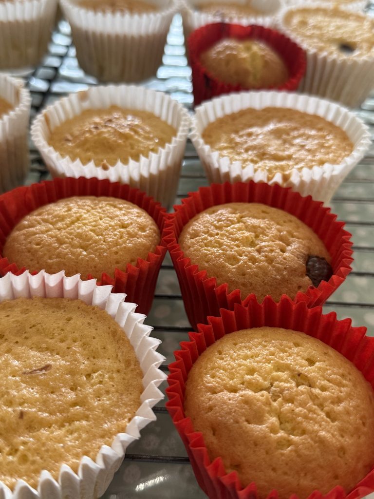 Freshly baked cupcakes cooling on a rack in colorful liners.