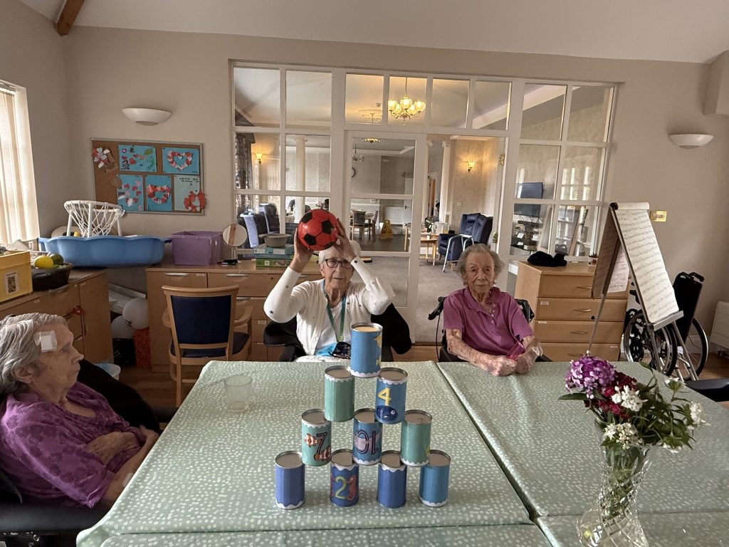 Seniors playing a ball game with stacked cans during an activity session.