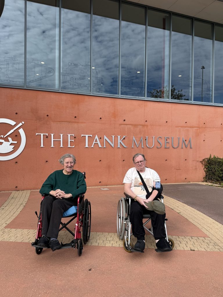 Two men in wheelchairs outside The Tank Museum building.