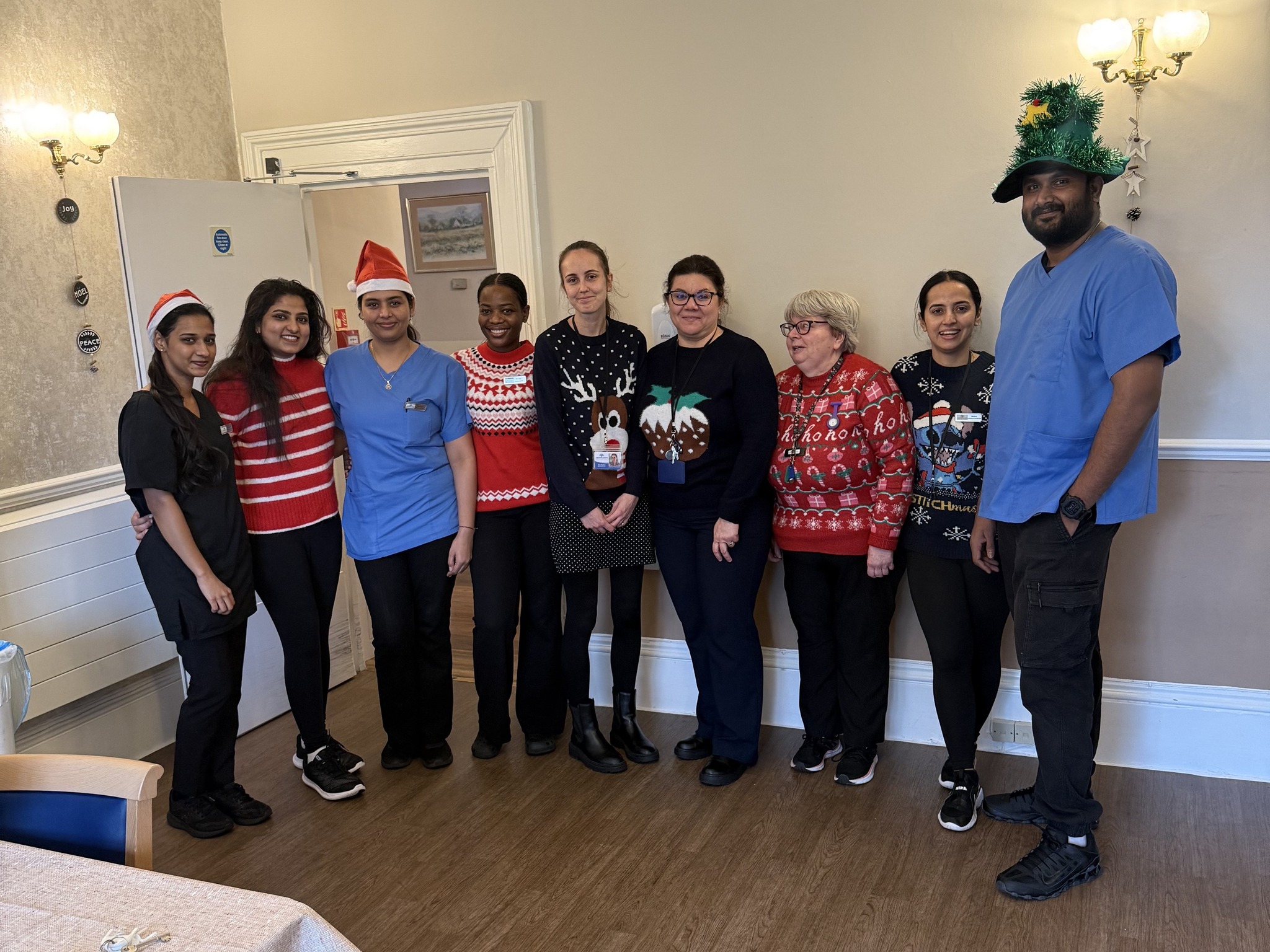 Group of staff in festive sweaters and uniforms posing together for a holiday photo.