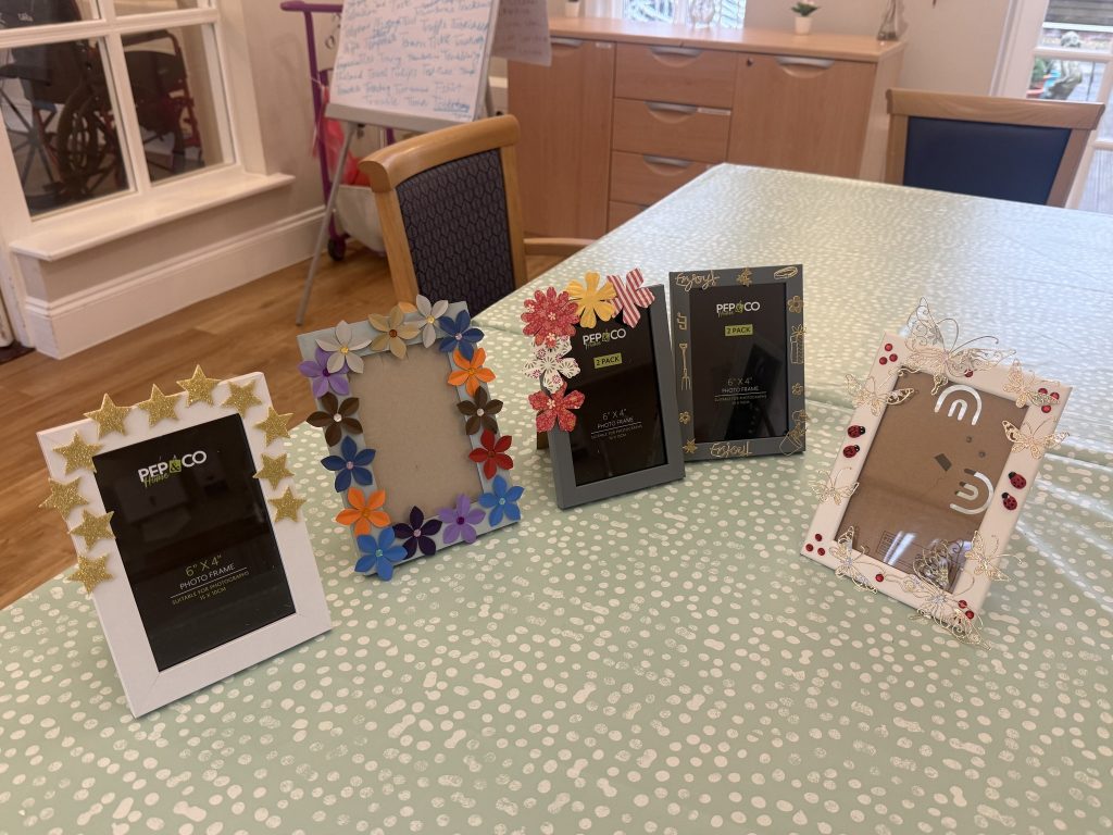 Decorated photo frames with stars, flowers, and butterflies displayed on a table.