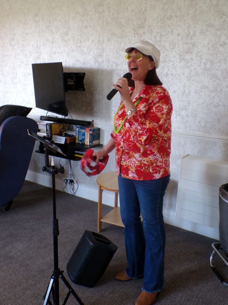 Woman singing into a microphone while holding a tambourine.