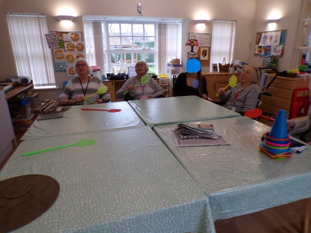 Elderly group seated at a table playing a light activity game with colorful paddles.