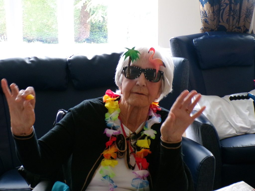 Elderly woman wearing flamingo sunglasses and colorful party garland.